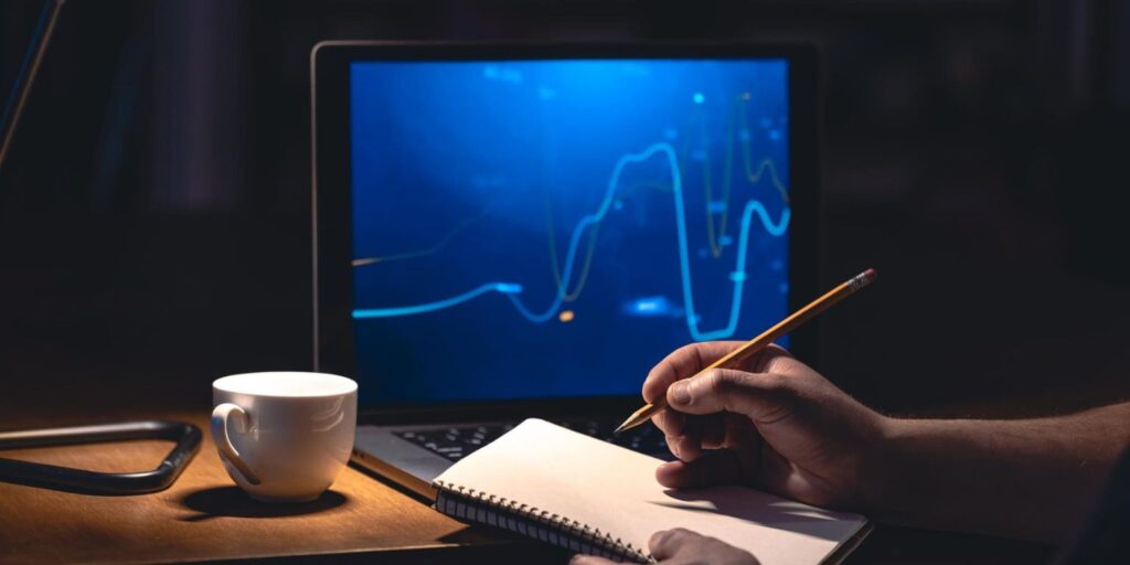 Trader iniciante analisando gráficos de ações em notebook — foco em plataformas para começar.